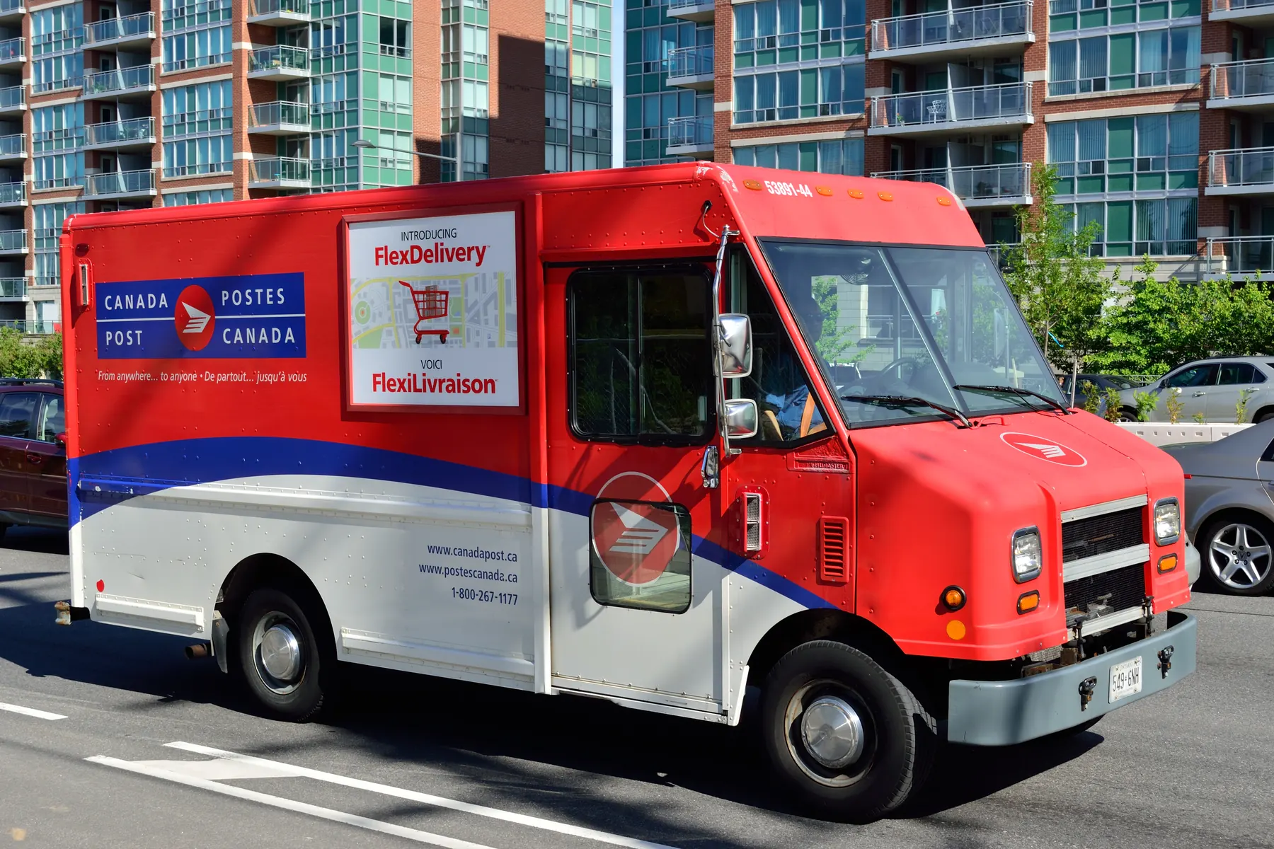 A Canada Post delivery truck advertising FlexDelivery parcel service drives past condo towers on Highway 7 in Markham, Ontario