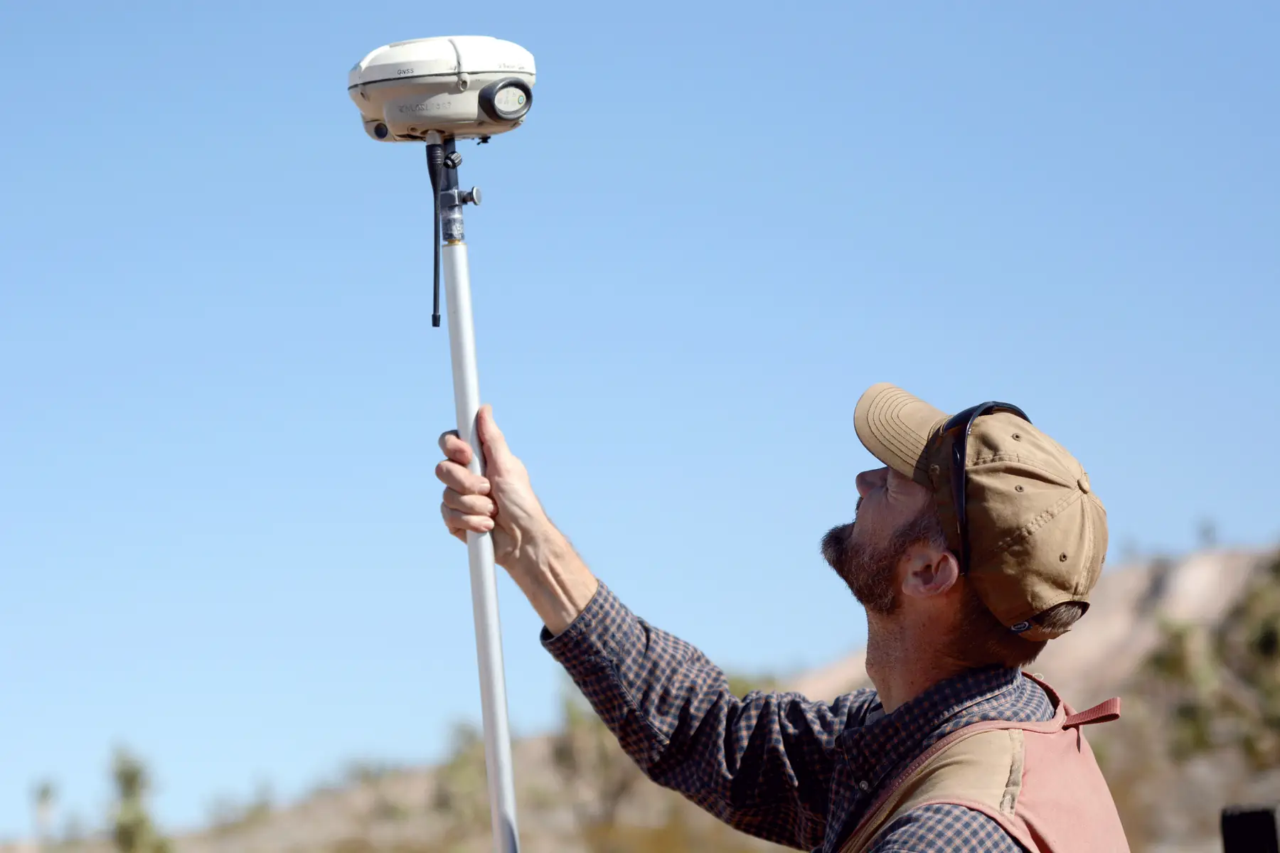 A land surveyor raises a GNSS receiver on a survey pole during a boundary re-survey in Utah