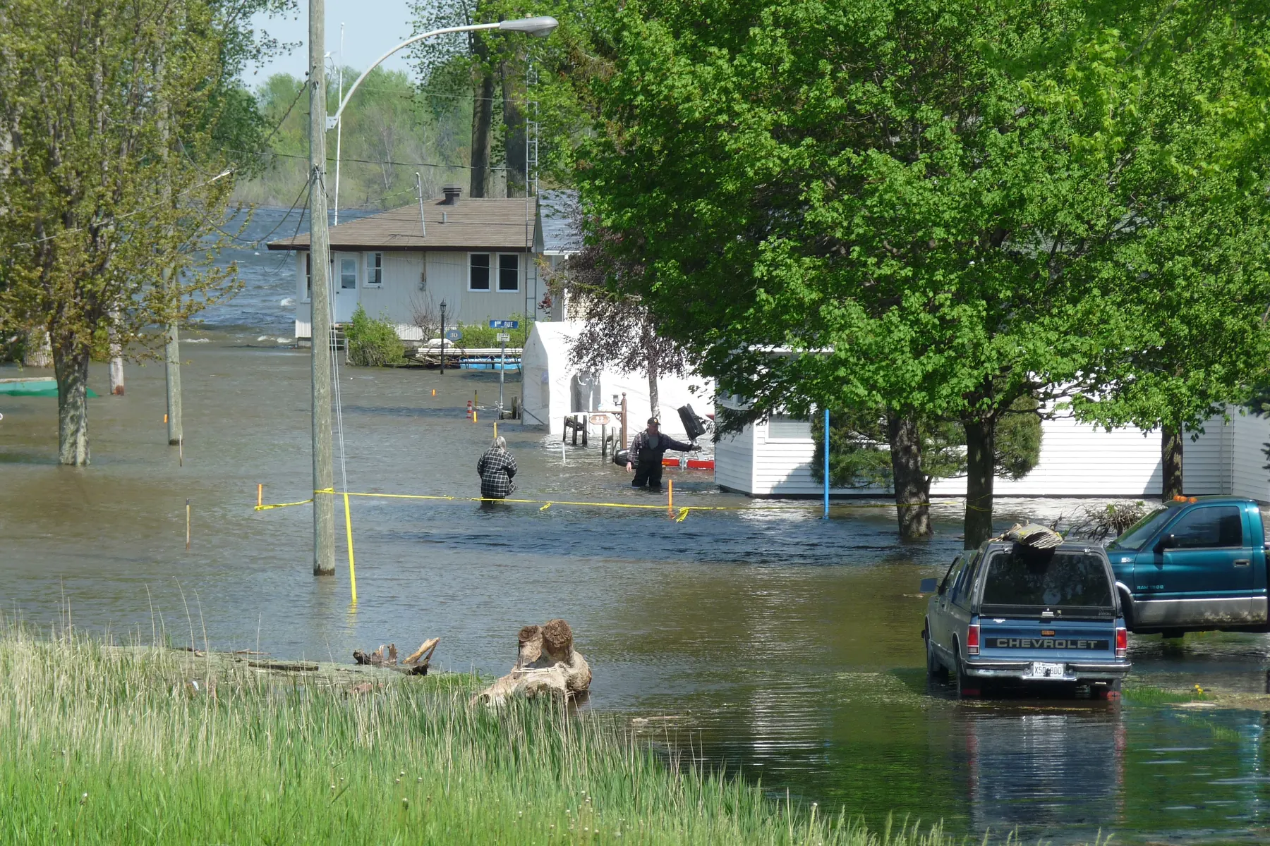 Floodwater surrounding cottages and pickup trucks on a street beside the Richelieu River in Quebec